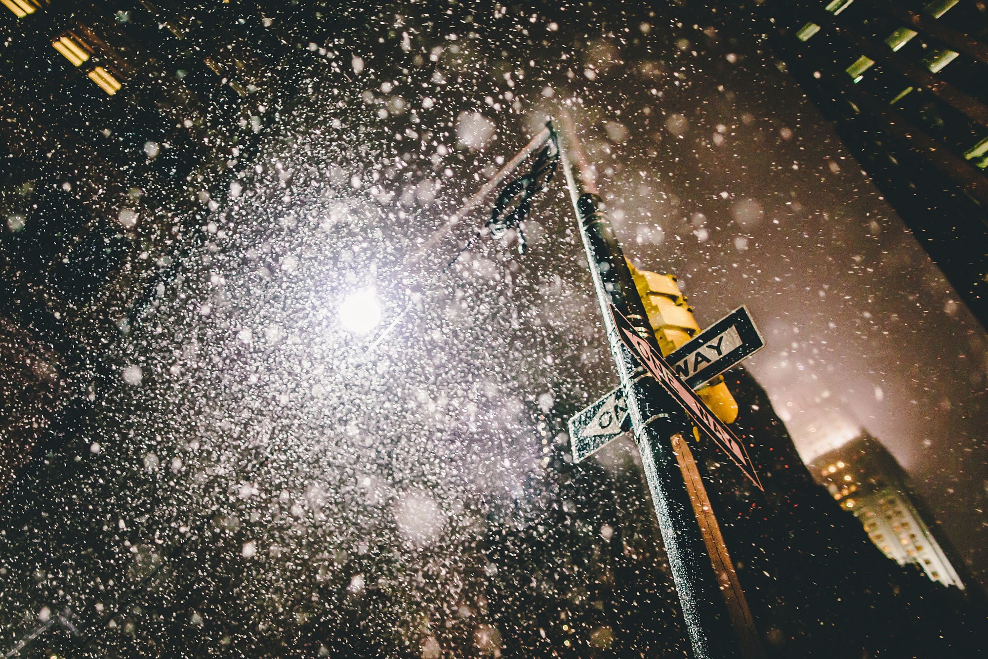 green and white one way road sign New York City snow bokeh 2k