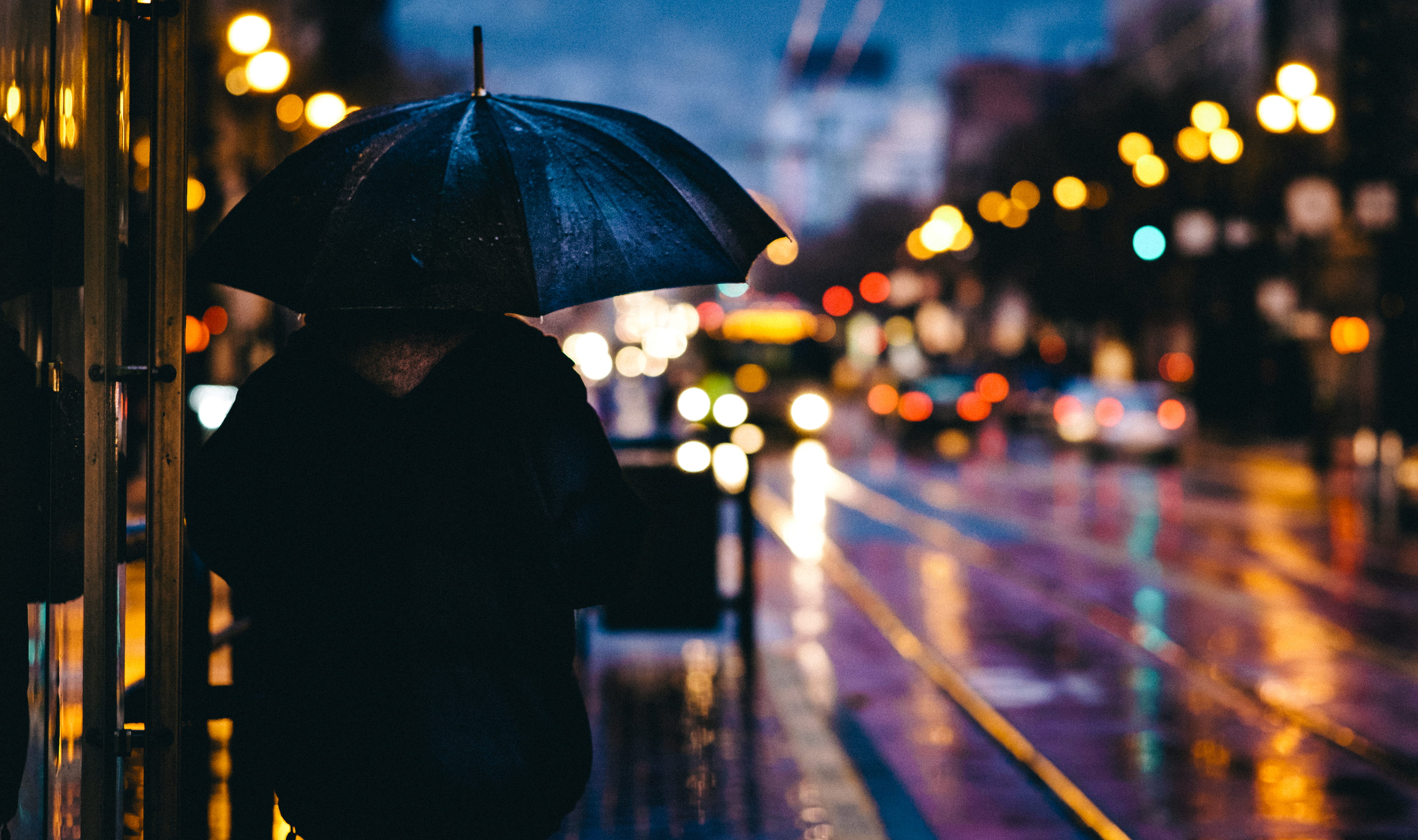 person walking on street while holding black umbrella near cars road at nighttime 2k 4k