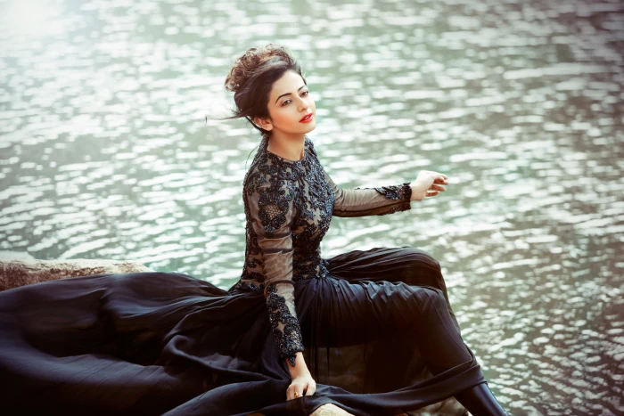 woman with black long sleeved floral crew neck dress sitting by the water during daytime