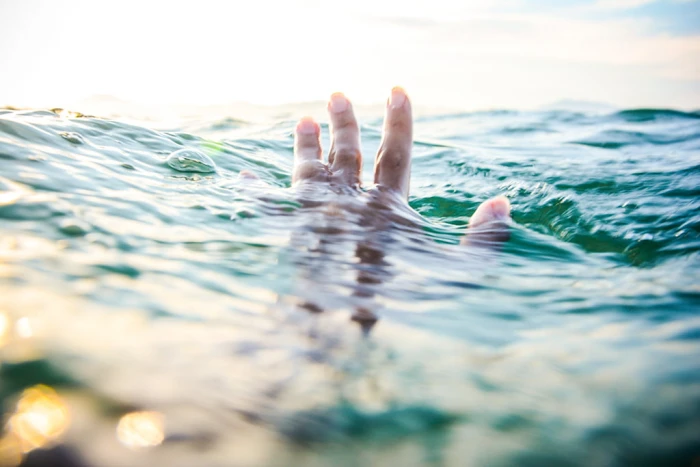 tilt shift lens photography of persons hand above body water and his under the