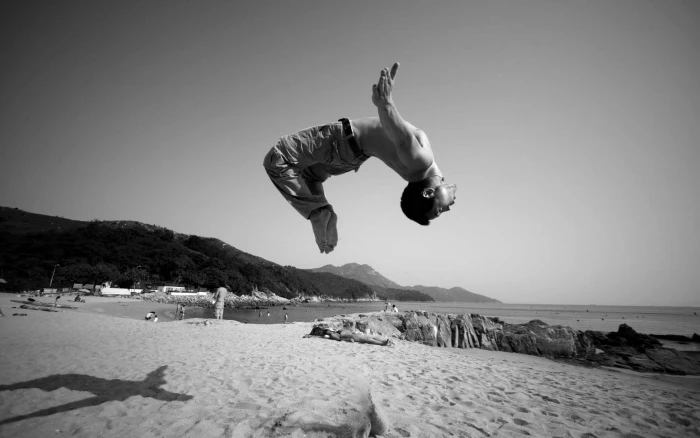 monochrome jumping men beach sand shadow shirtless full length 2k