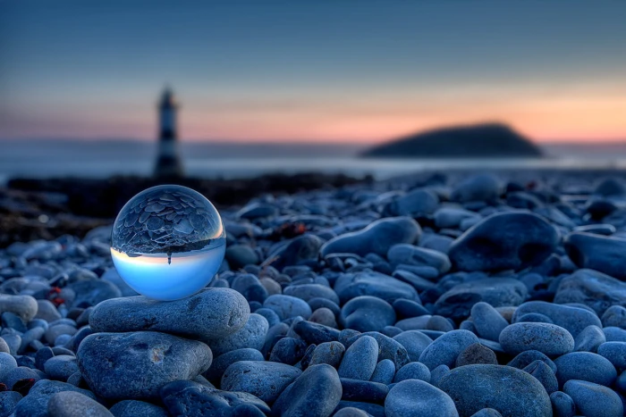 ball on gray stones near lighthouse at golden hour Beach