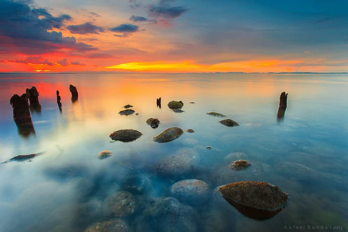 landscape photography of body water with rocks during golden hour