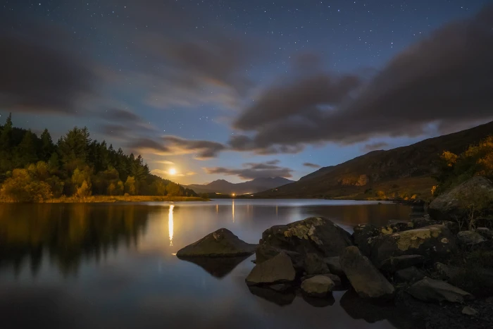 two mountain beside a body of water during sunset snowdonia 2k