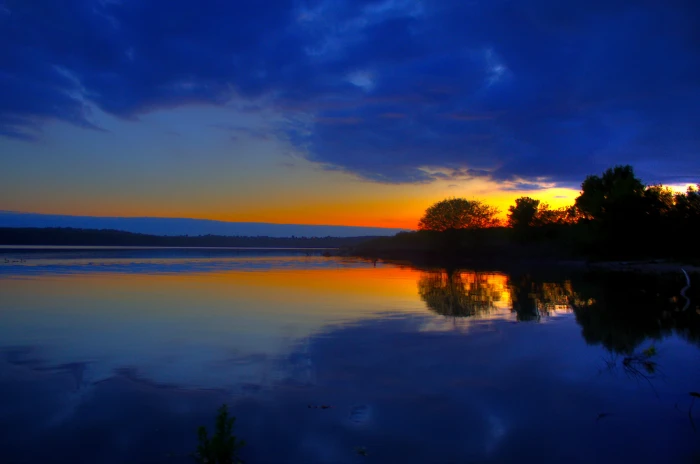 calm body of water during golden hour sunset lake trees orange 2k