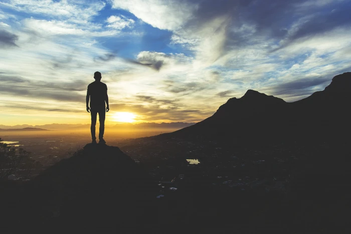 person standing at the top of mountain silhouette photography man on cliff during golden hour 2k