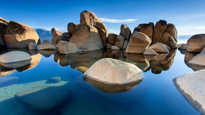body of water near rocks nature sky blue landscape solid 2k