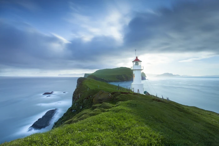 white lighthouse on green field hills mykines faroe islands 2k