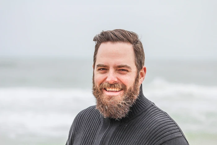 Man Wearing Black Zip up Jacket Near Beach Smiling at the Photo 2k