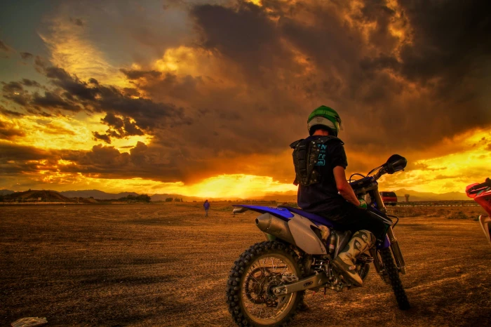 photo of man riding motocross dirt bike under nimbus clouds Dirt Track 2k