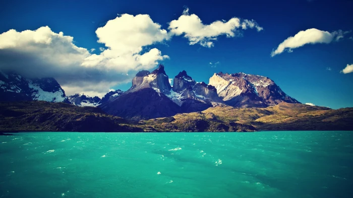 rock formation and body of water near mountains under cloudy sky 2k