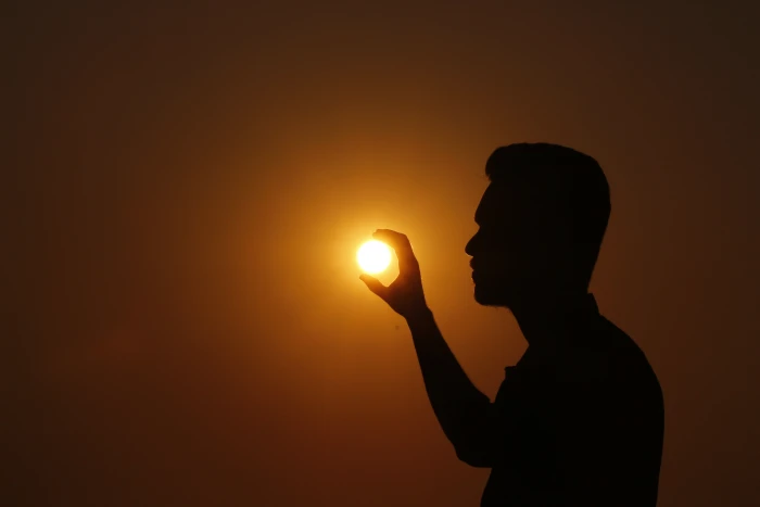forced perspective photo of silhouette man holding sun sunset 2k 4k 5k