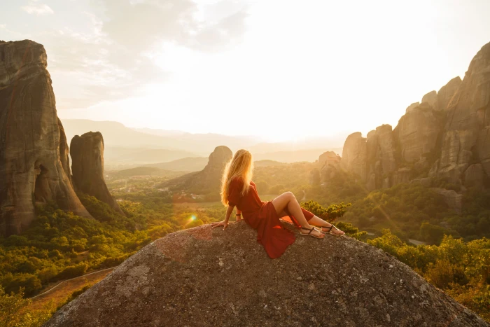 woman sitting on gray rock wearing red dress formation at daytime 2k