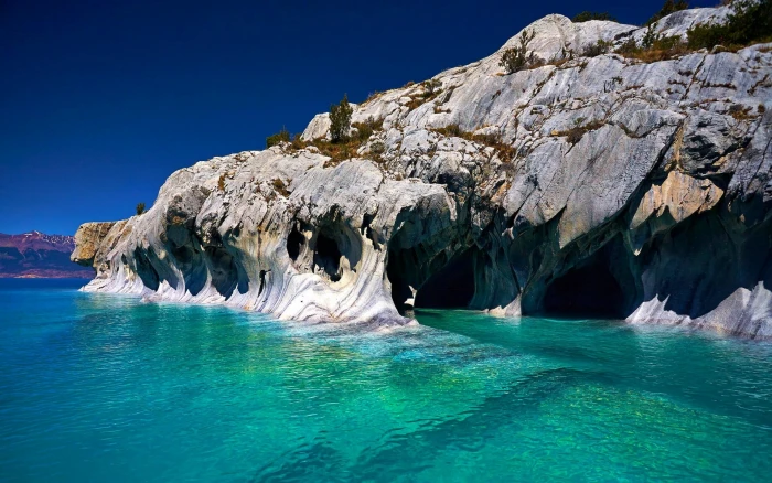 gray rock mountain beside body of water nature landscape cave 2k