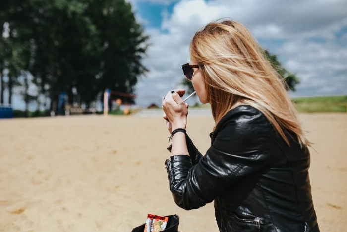 Young woman wearing a leather jacket and sunglasses on the beach 2k 4k