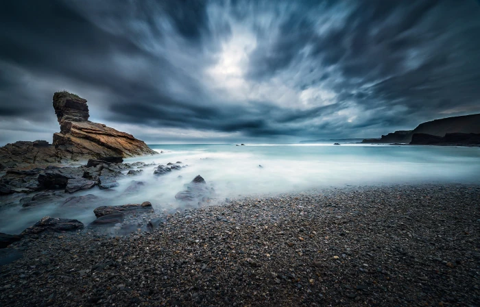 stones on seashore under clouded sky Alone in the dark landscape 2k