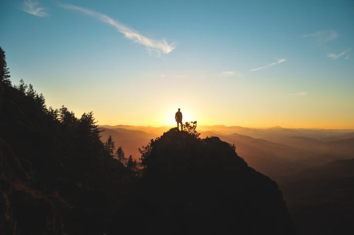 silhouette of man standing on mountain peak hill facing sunset 2k 4k