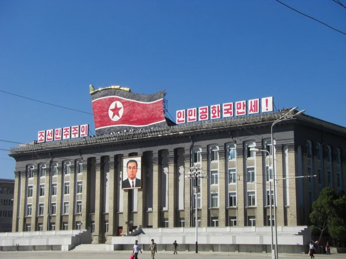 red flag on roof top north korea pyongyang building kim il sung square 2k