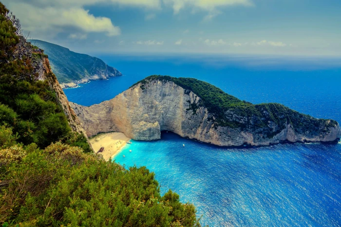 green and brown mountain beside body of water landscape beach 2k