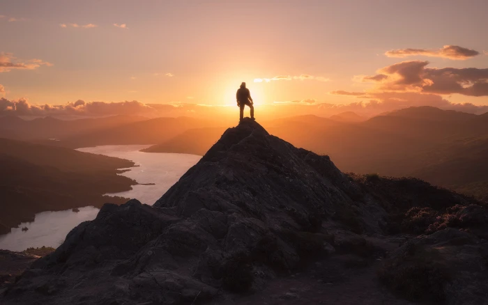 man standing on tip of mountain during golden hour Sunset Scotland 2k