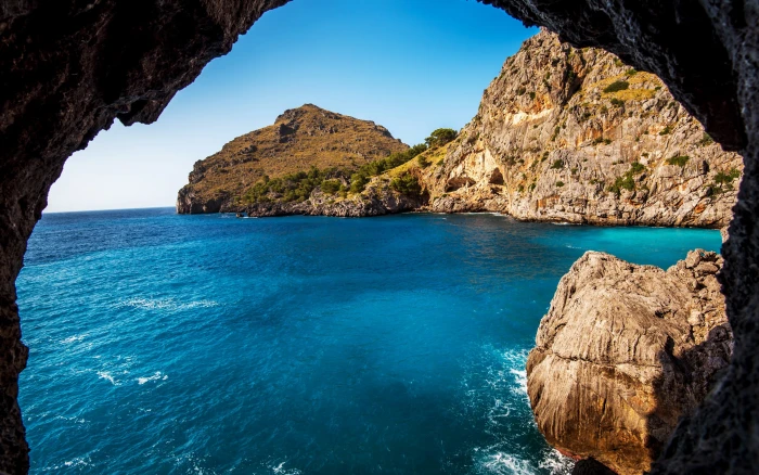 brown rock formation and body of water beach sea blue green 2k