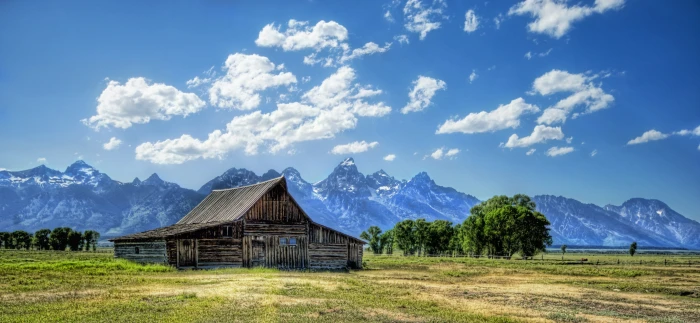 brown wooden house on middle of green grasses photo during daytime wyoming 2k 4k