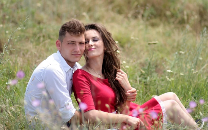 woman and man near each other while sitting on grass field during daytime 2k 4k