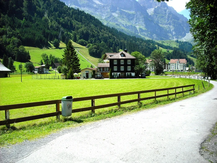 brown and black concrete house near mountain at daytime road through village 2k