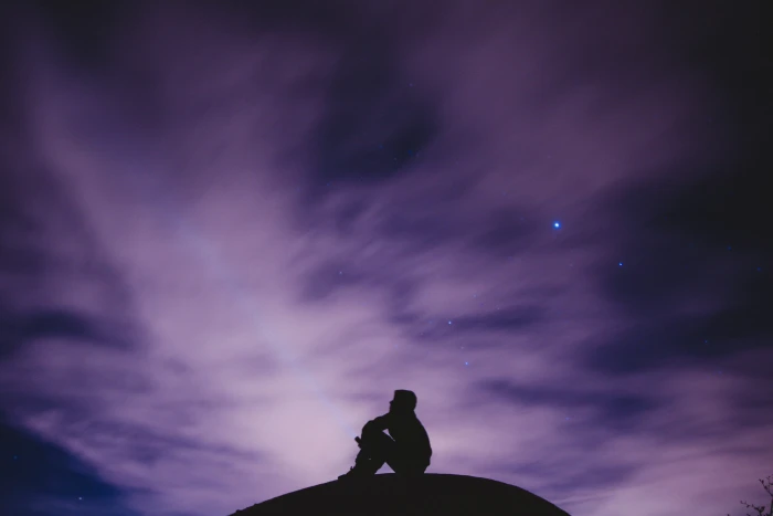 person sitting on black surface looking to sky silhouette photography of ground 2k 4k 5k