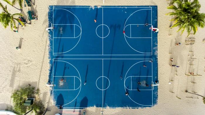 aerial photography of basketball court view blue in the middle sand with coconut trees 2k 4k