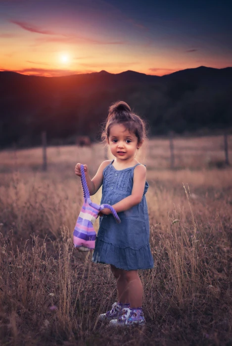 girl wearing blue chambray spaghetti strap dress holding purple striped bag during sunset 2k