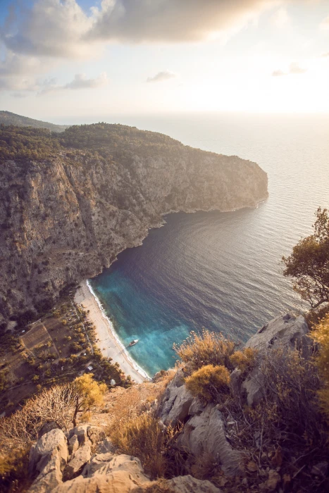 landscape photography of body water and clff white boat on the during daytime 2k