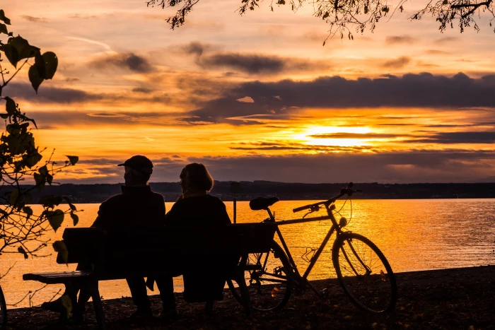 silhouette of man and woman sitting on bench facing body water 2k 4k 5k