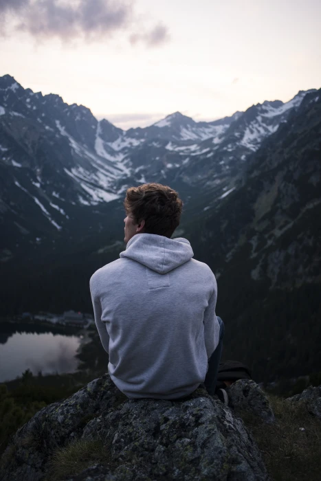 photo of man sitting on rock facing mountain alone lake nature 2k 4k