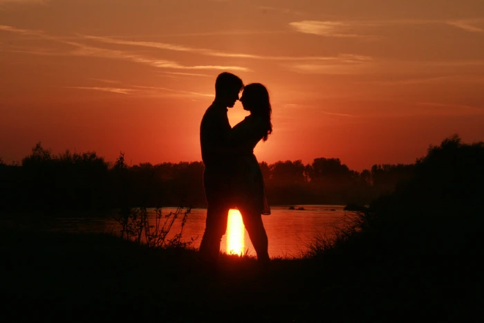 silhouette of couple standing beside body water against sun ray 2k 4k