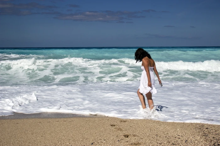 woman in white tube flare mini dress walking on seashore under blue sky during daytime 2k 4k 5k