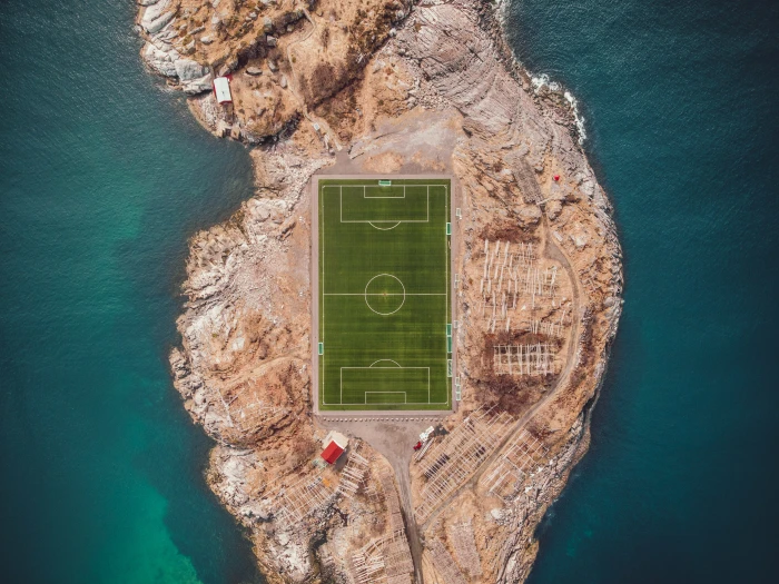 aerial photography of soccer field near body water bird s eye island with in the middle 2k 4k
