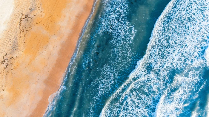 seawaves beside brown sand aerial photography of ocean wave 2k 4k