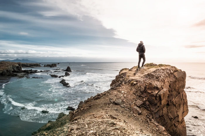 man on edge of cliff standing in front sea adventure 2k 4k 5k
