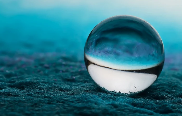 white and blue marble toy clear glass ball on top of soil 2k
