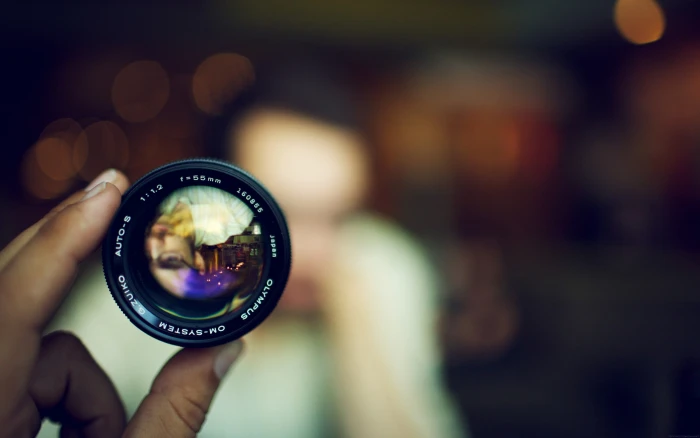 black camera lens person holding bokeh face blurred 2k