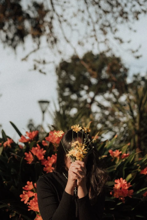 woman hiding her face with yellow flowers during daytime plant 2k 4k