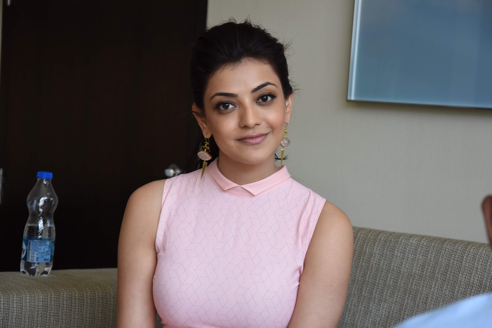 woman wearing pink collared sleeveless top sits and smiles inside white painted room 2k 4k 5k