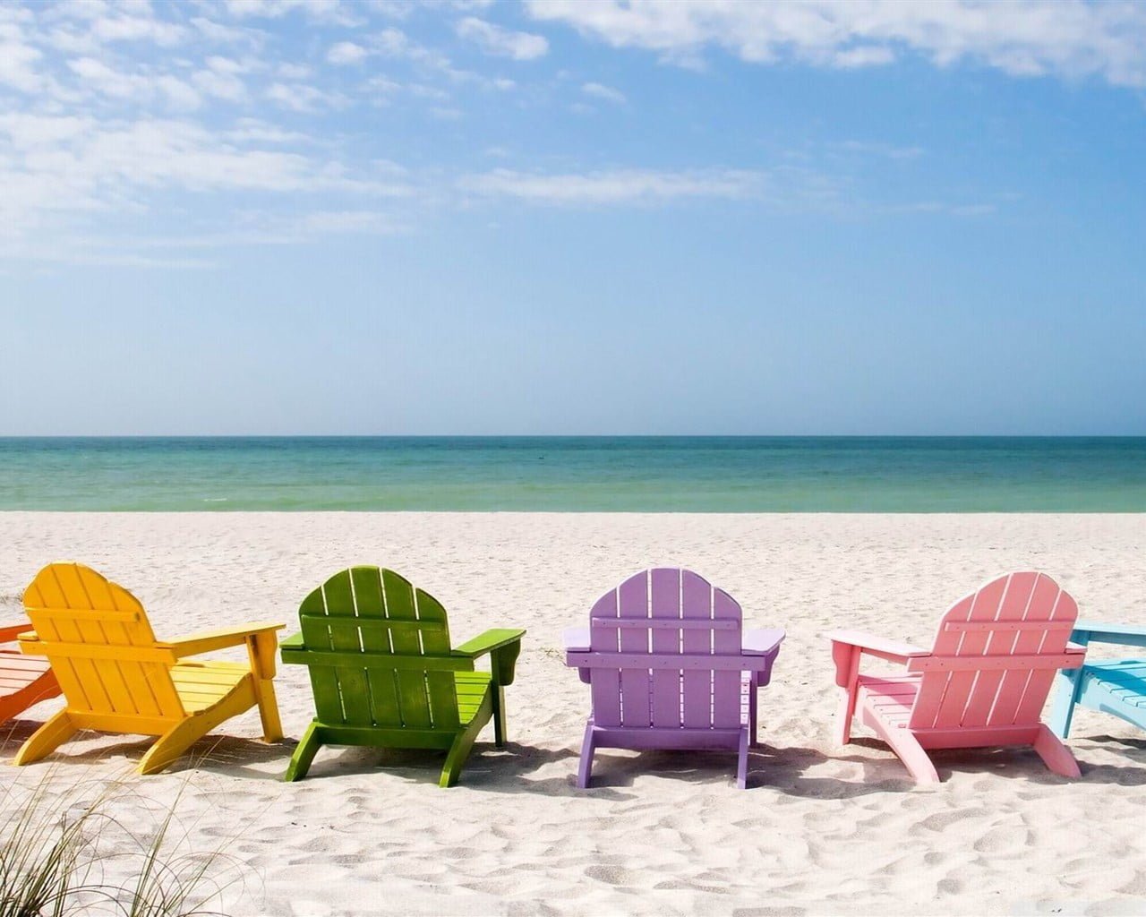 yellow green purple and pink wooden adirondack chairs deck