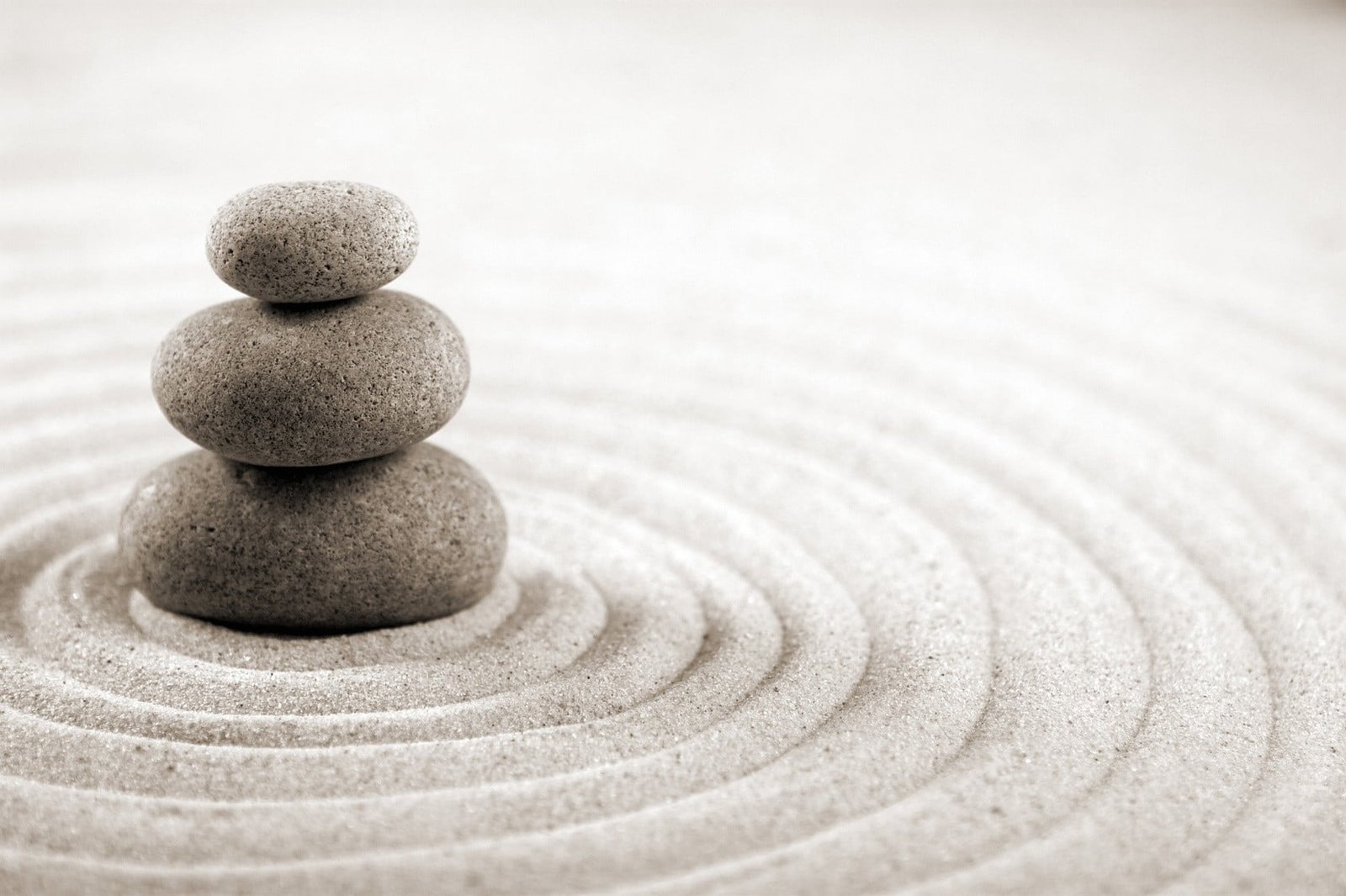 cairn on sand three brown concrete stones circle blurred depth of field 2k