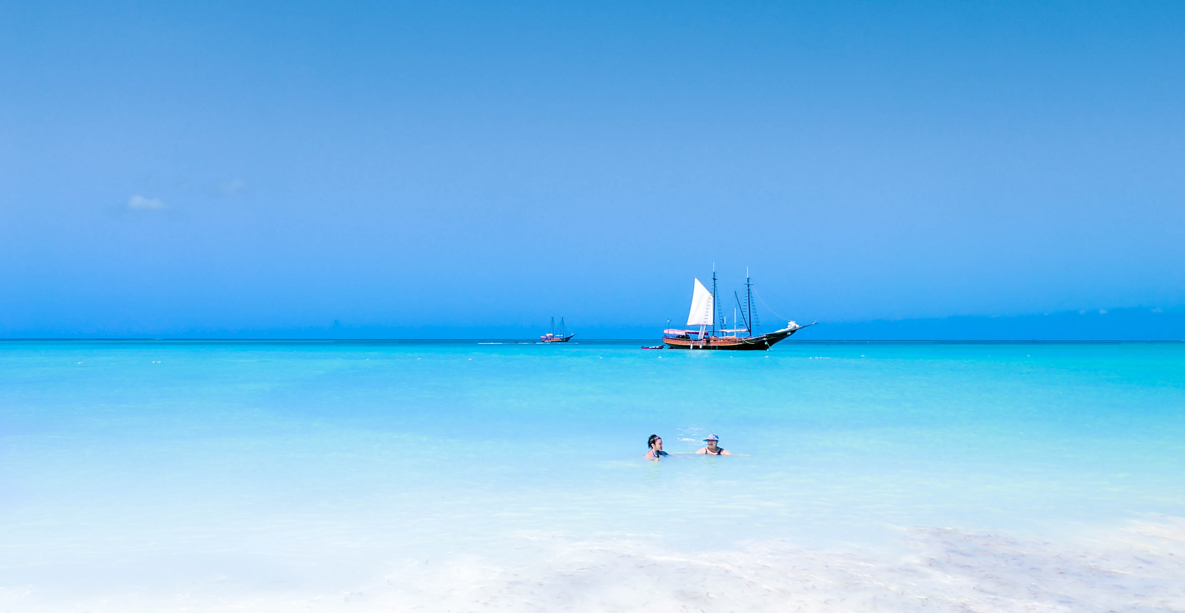 brown and white galleon boat on body of water near beach aruba 2k 4k