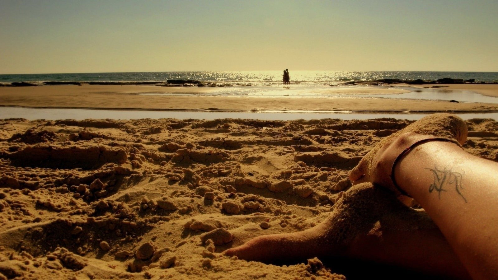 brown and black wooden table beach sand feet people land 2k
