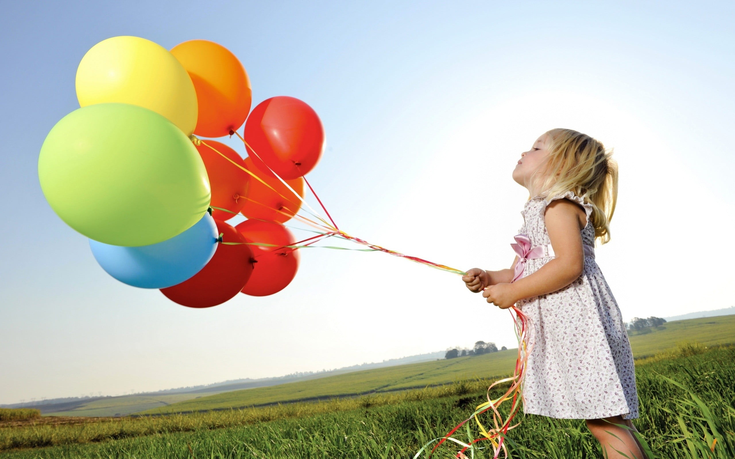girl in white dress holding assorted color balloons little 2k