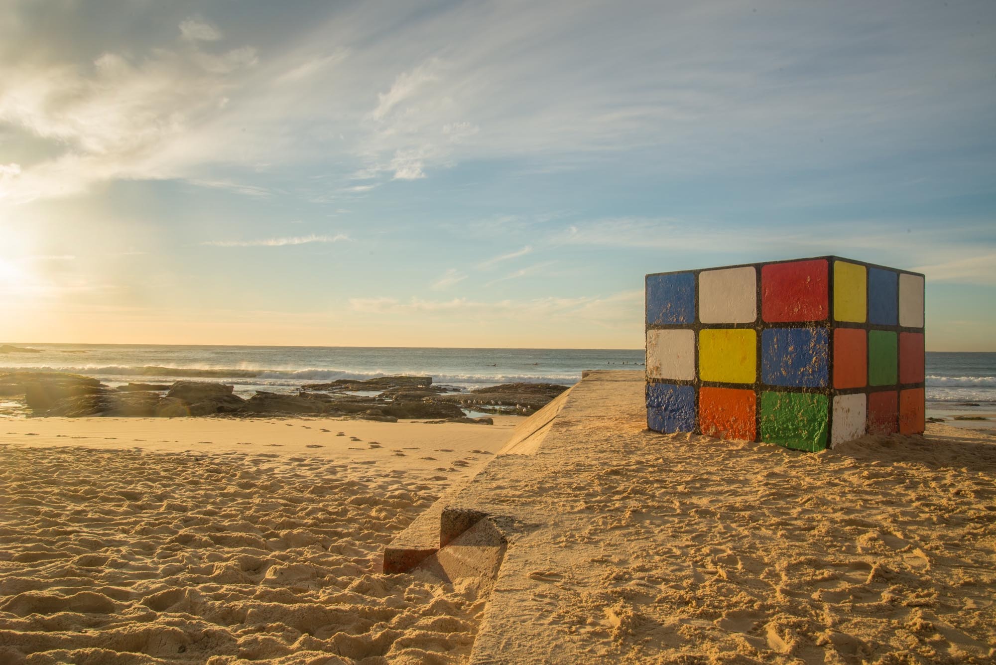 selective focus photography of Rubik's cube on beach sand 2k
