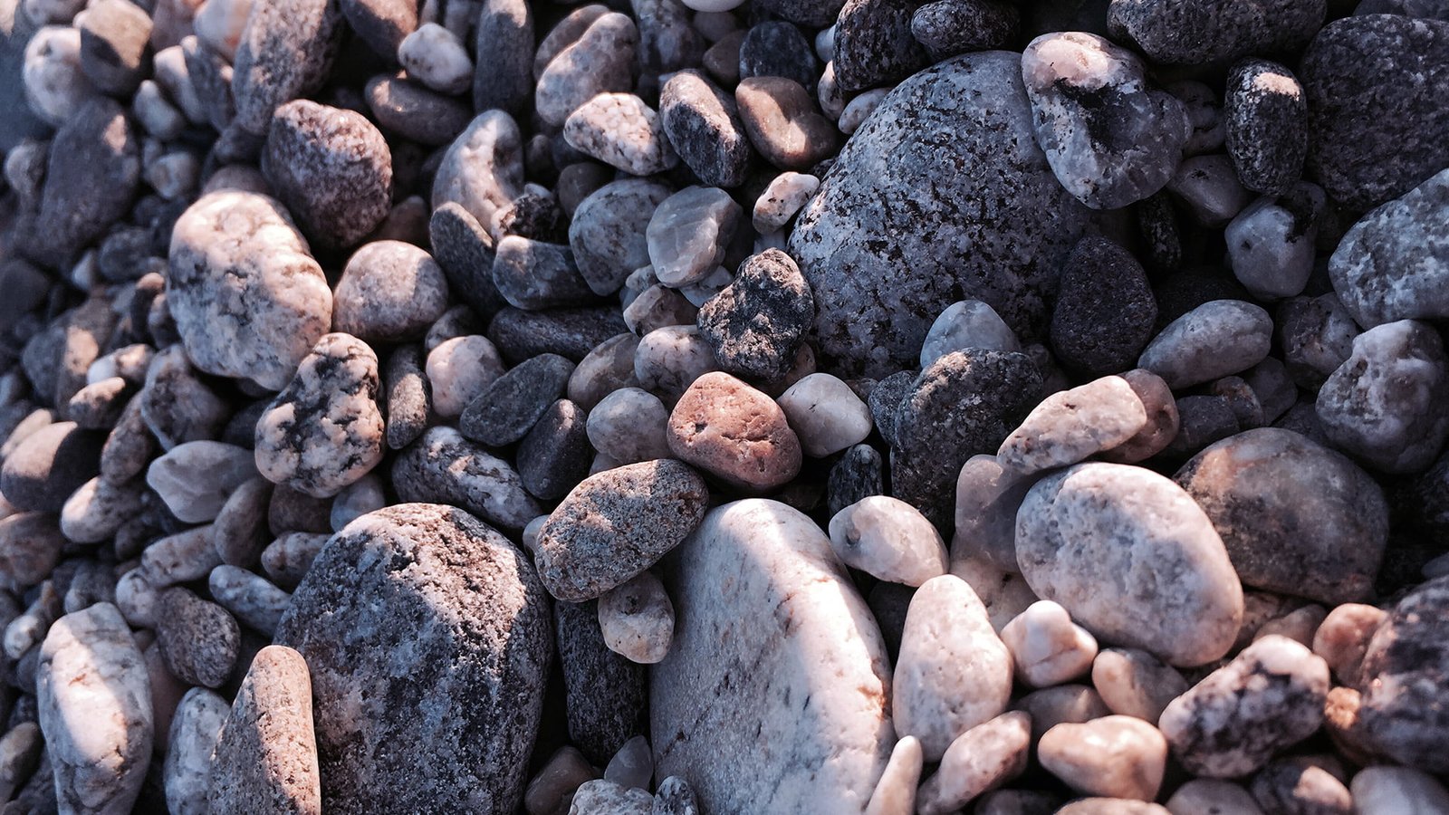 assorted brown and black stones beach full frame large group of objects 2k